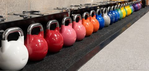 A long row of colour-coded kettlebells along the edge of the training floor