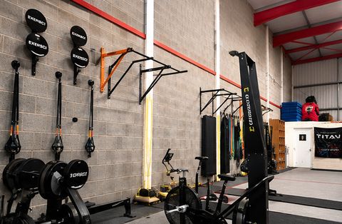 Wall-mounted suspension trainers, pull-up bars and resistance bands beside conditioning machines