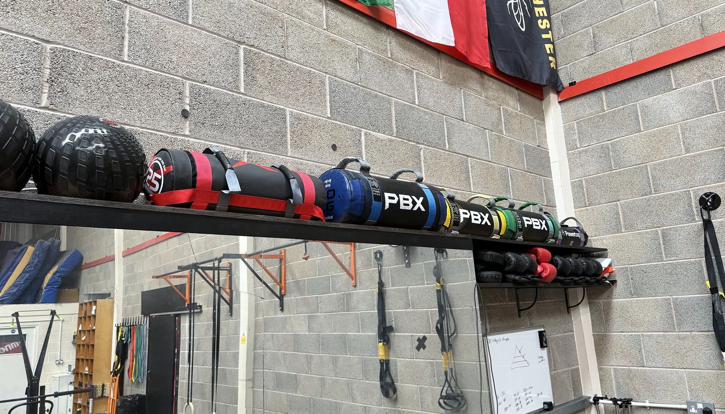 Resistance bands and training kit racked along the wall above the flags on the training floor